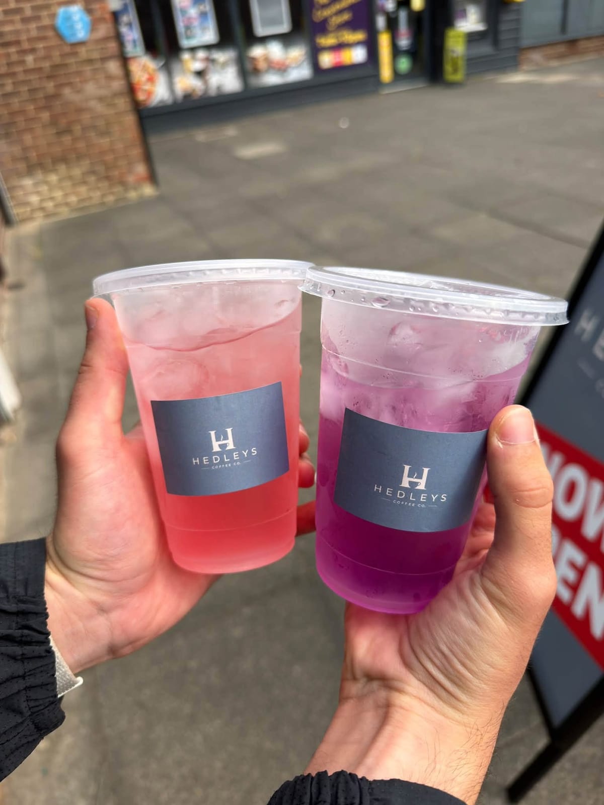 Two iced lemonades, one pink and one purple, held up on The Avenue