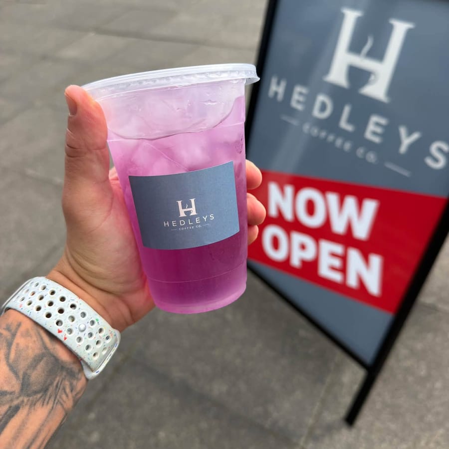A purple iced lemonade held up outside the cafe