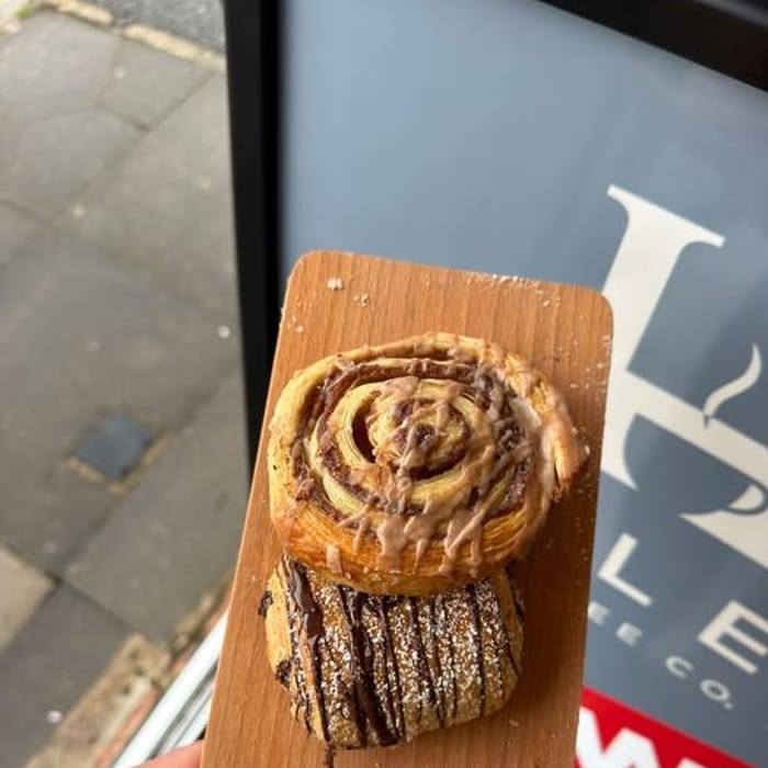 A cinnamon swirl and a chocolate pastry on a wooden board