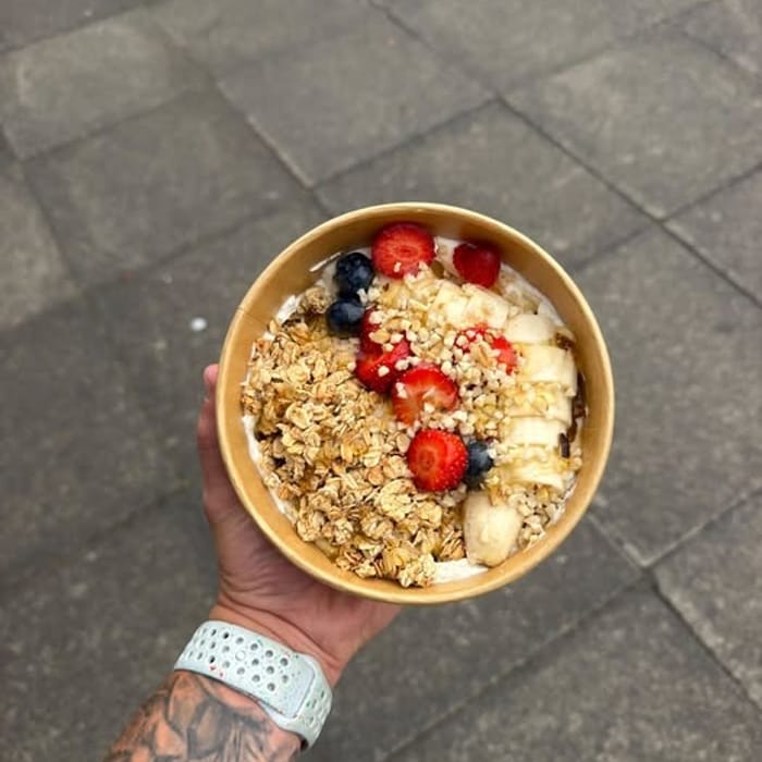 A yoghurt bowl with granola, banana, strawberries and blueberries
